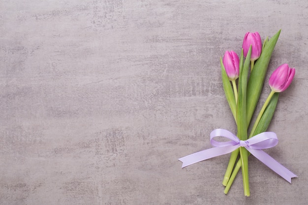 Carte de voeux de printemps, tulipes de couleur rose sur fond gris.