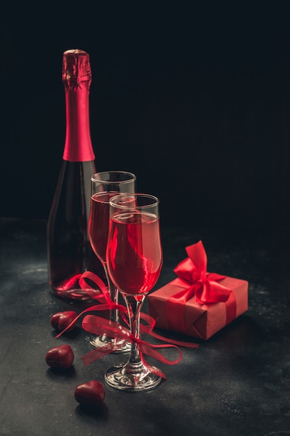 Carte de voeux Saint Valentin et anniversaire avec champagne et bonbons coeur sur fond noir.