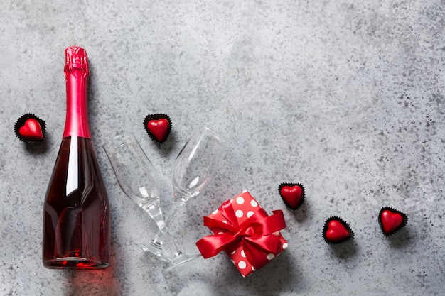 Carte De Voeux Saint Valentin Avec Bouteille De Vin Mousseux, Boîte Cadeau, Bonbons En Forme De Coeur Sur Fond Gris. Concept De Rencontres Romantiques. Vue D'en-haut.