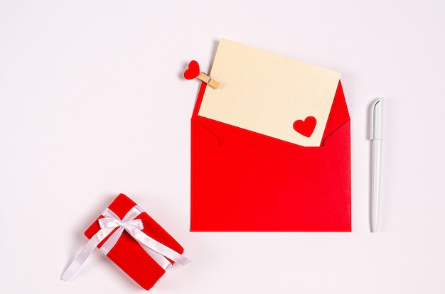 Carte de voeux Saint Valentin avec enveloppe rouge, coeurs et coffret cadeau sur fond blanc avec espace copie