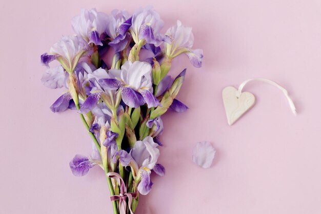 Carte de voeux avec souhaits pour un bon après-midi d'été un bouquet d'iris bleus sur fond pastel un coeur en céramique vue de dessus espace pour le texte