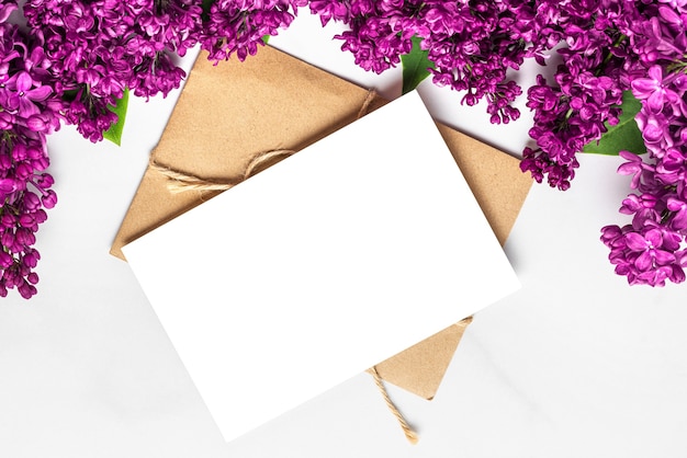 Carte de voeux vierge avec des fleurs en fleurs lilas printanières sur une surface blanche
