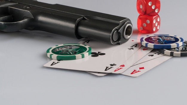 Cartes de jetons de poker et arme à feu sur fond blanc Jeux de hasard et divertissement Casino et poker