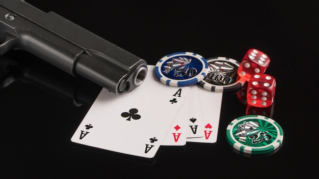 Cartes de jetons de poker et une arme à feu sur fond noir Le concept de jeu et de divertissement