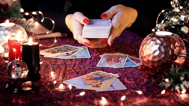 Des cartes de tarot floues sur la table près des bougies allumées, un devin lisant sur la décoration de Noël.