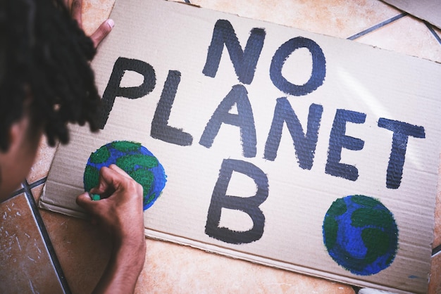 Carton environnemental et affiche pour protester contre le changement climatique, le réchauffement climatique et le jour de la terre Vert et écologie mondiaux avec un homme noir dessinant un signe créatif pour la crise environnementale et énergétique