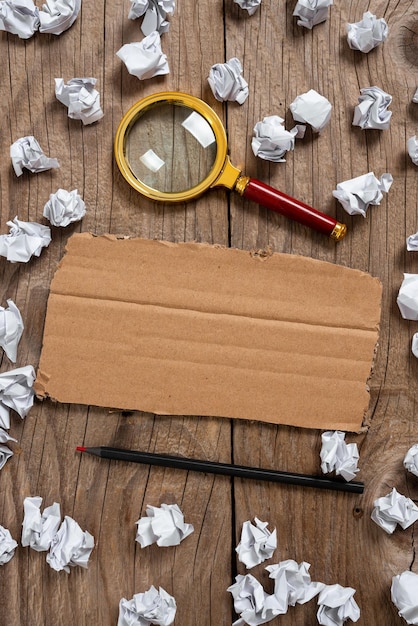 Photo carton avec des informations importantes avec du papier enveloppe un crayon et une loupe autour du carton avec un message crucial avec des notes froissées partout et un crayon