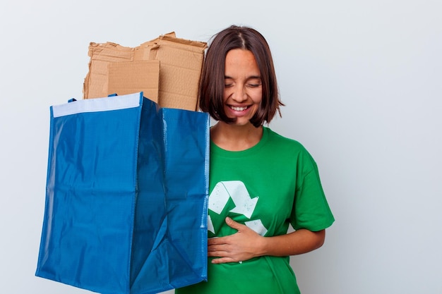 Carton de recyclage femme jeune métisse isolé sur mur blanc en riant et en s'amusant.