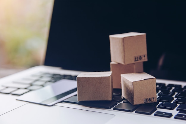 Cartons en papier ou colis avec un logo de panier et une carte de crédit sur un clavier d'ordinateur portable