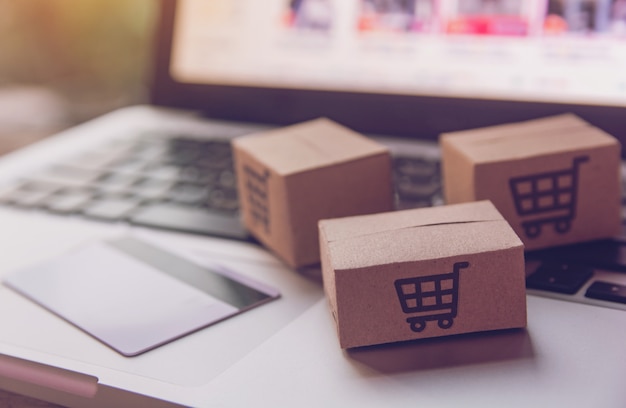 Cartons en papier avec un logo de panier et une carte de crédit sur un clavier d'ordinateur portable.