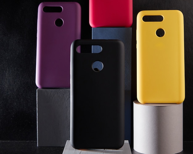 Les cas colorés pour les smartphones modernes se tiennent sur des supports sur la table un objet en arrière-plan flou