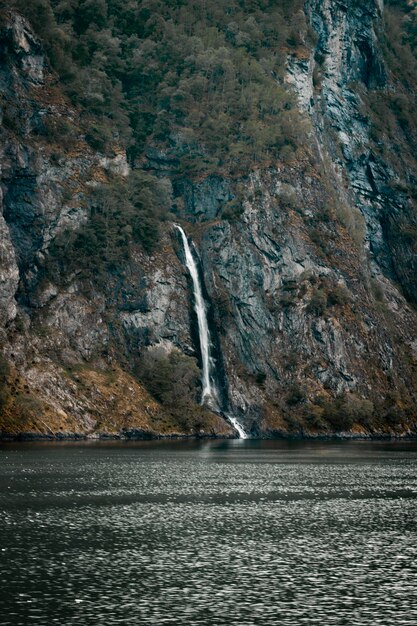 Une cascade dans un fjord avec un bateau au premier plan