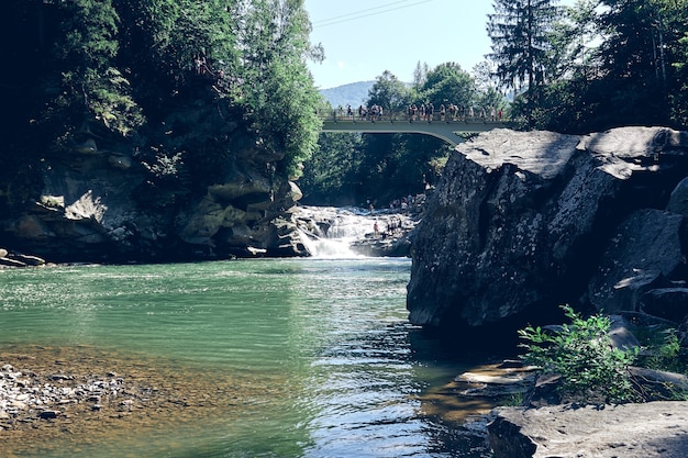 Une cascade descendant d'une falaise abrupte . Eau claire bleue de montagne la rivière. Pierres rocheuses et forêt paysage alpin.