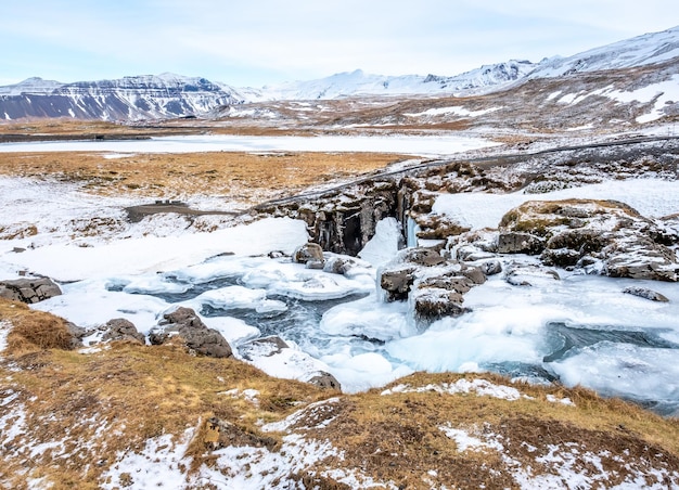 La cascade de Kirkjufellfoss avec sa vue environnante sur l'eau gèle le monument le plus populaire d'Islande