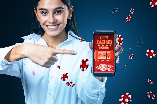 Casino en ligne et jeu de hasard sur le concept d'appareil Cheerful woman pointing at smartphone with creative slot machine and other games