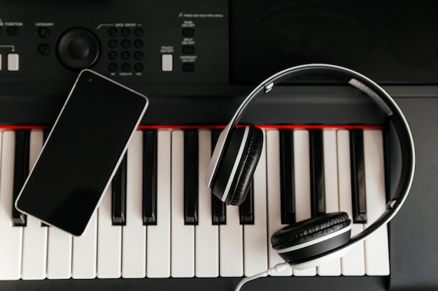 Casque blanc et smartphone sur clavier de synthétiseur musical Casque sur piano électronique