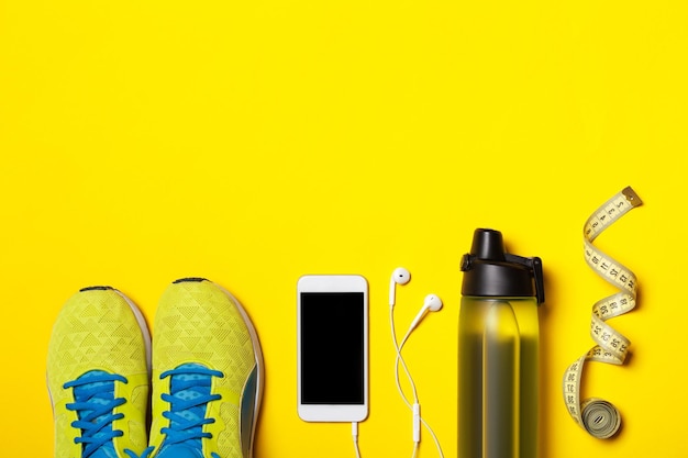 Casque blanc téléphone intelligent et baskets jaunes sur fond jaune Concept de mode de vie actif
