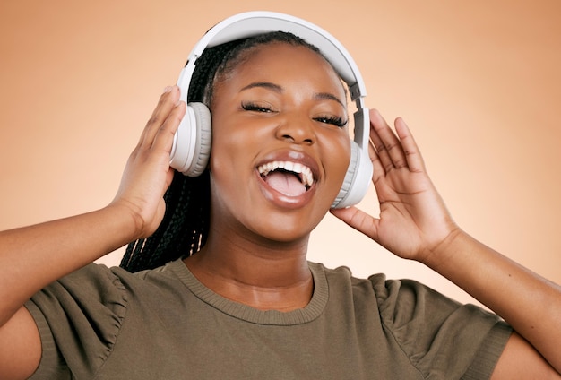 Casque chantant et portrait de femme isolée sur fond de studio dans l'énergie de la santé mentale et la musique radio Voix de chanteur et les Noirs de la génération z écoutant la technologie audio sonore sur la maquette