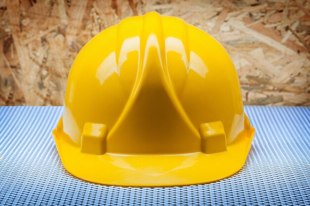 Casque de construction jaune sur fond de contreplaqué