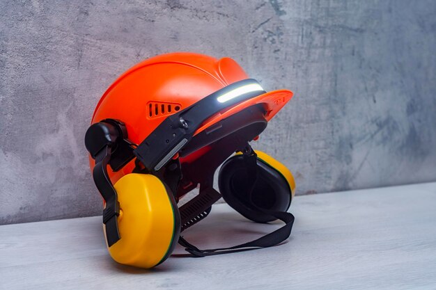 Photo casque de construction de protection pour la tête avec cache-oreilles et lampe frontale sur la table outil de construction et forme de protection