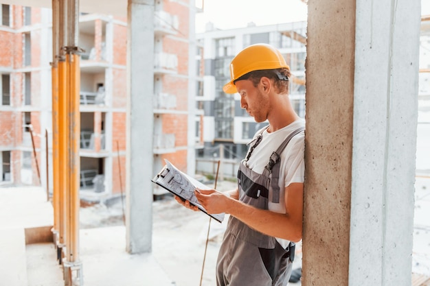 Casque de couleur jaune Jeune homme travaillant en uniforme à la construction pendant la journée