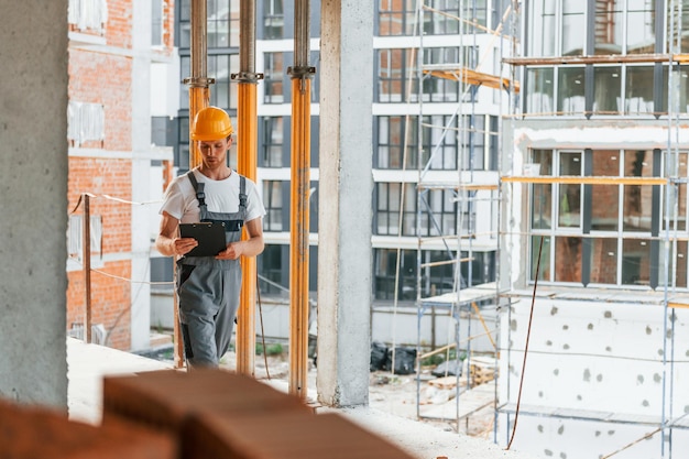 Casque de couleur jaune Jeune homme travaillant en uniforme à la construction pendant la journée