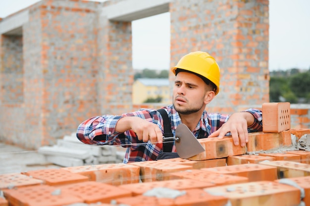 Casque de couleur jaune Jeune homme travaillant en uniforme à la construction pendant la journée