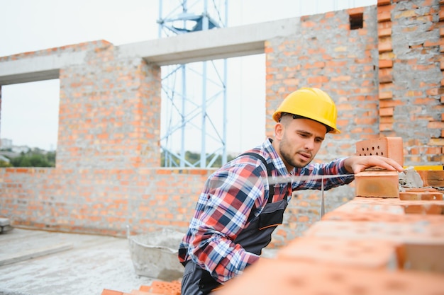 Casque de couleur jaune Jeune homme travaillant en uniforme à la construction pendant la journée