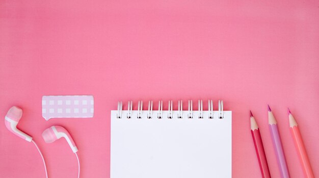 Casque et crayon de bloc-notes sur un fond rose