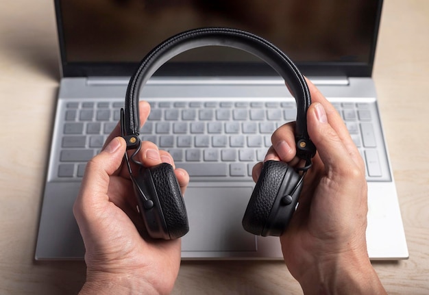 Casque dans les mains et ordinateur portable écoutant de la musique et concept de podcast