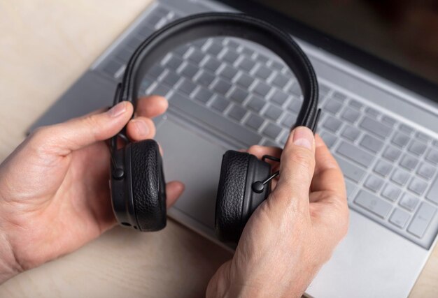 Casque dans les mains et ordinateur portable écoutant de la musique et concept de podcast