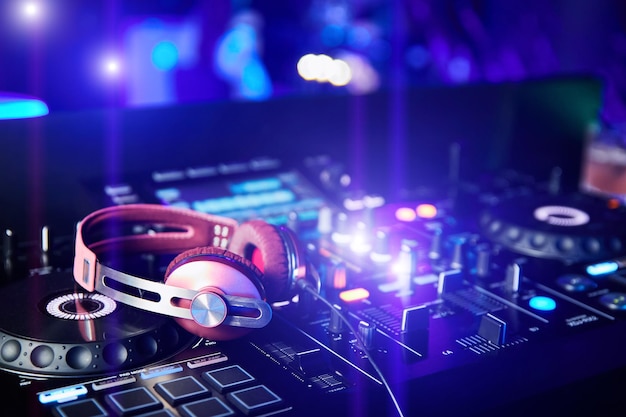 Casque DJ rose sur table de mixage et platines en boîte de nuit