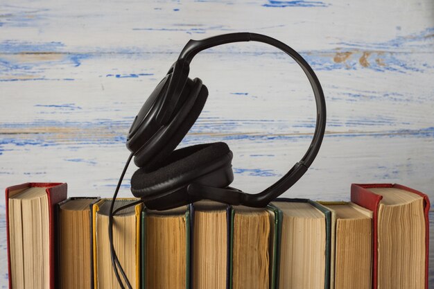 Casque d'écoute sur des livres pliés sur le fond en bois blanc