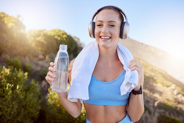 Casque d'entraînement nature et musique en streaming d'une femme heureuse après l'exercice par les montagnes Remise en forme santé et sport personne après l'entraînement buvant de l'eau avec le sourire se sentant libre avec bonheur