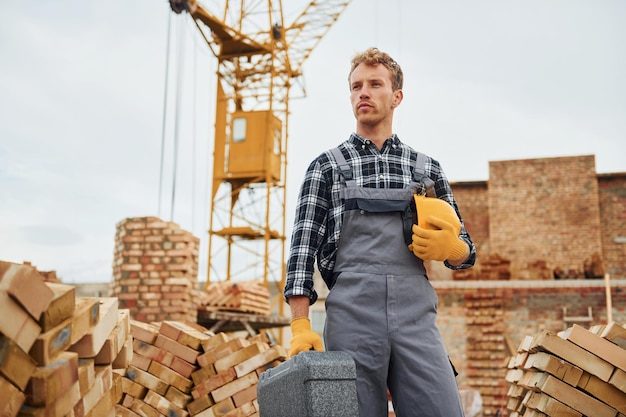 Casque et étui dans les mains Travailleur de la construction en uniforme et équipement de sécurité ont un travail sur la construction