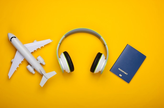 Casque, figurine d'avion, passeport sur surface jaune