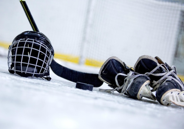 Casque de hockey, rondelle, bâton et patins sur la patinoire de hockey