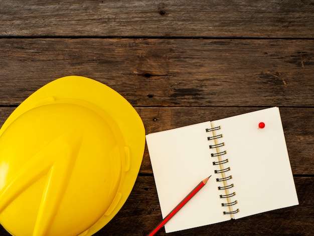 Casque jaune et un crayon sur le cahier