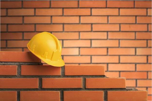 Casque jaune sur fond de mur de briques