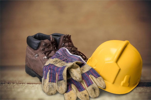 Casque jaune, gants avec des bottes sur fond de bois