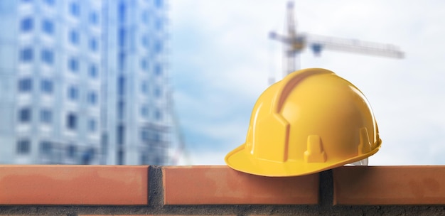 Casque jaune sur un mur inachevé de briques sur le fond de la construction