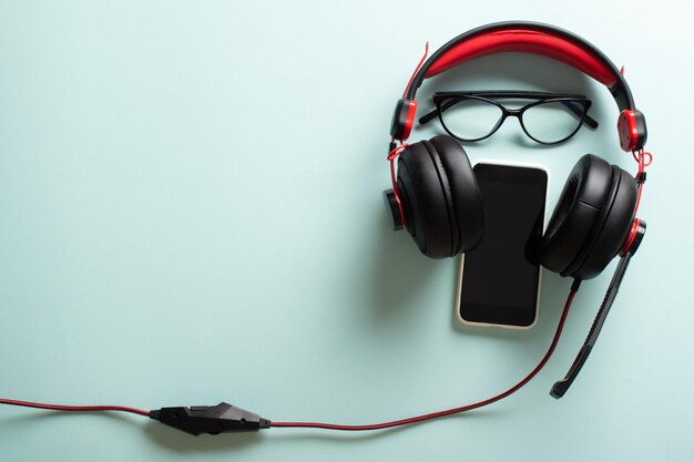 Casque avec lunettes et smartphone sur fond bleu clair Le bureau d'un blogueur moderne avec une place pour le texte