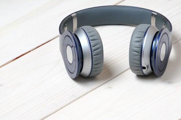 Casque moderne bleu et argent pour écouter de la musique sur un bois blanc