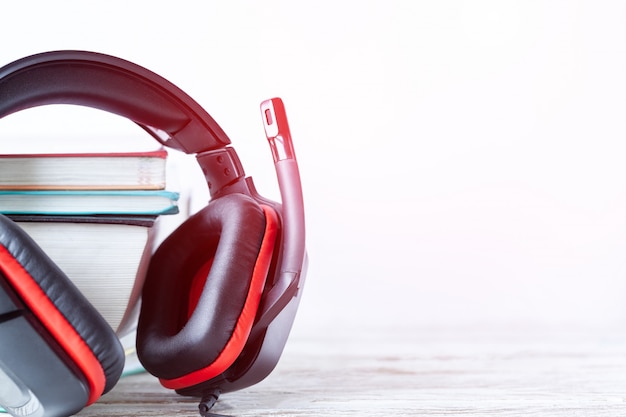 Casque moderne et livres sur table sur fond blanc. Concept de livre audio.