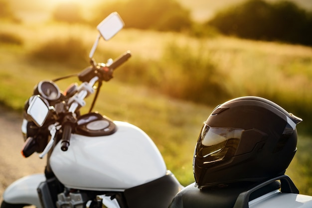 Un casque de moto repose sur un siège de moto dans les rayons du soleil couchant.