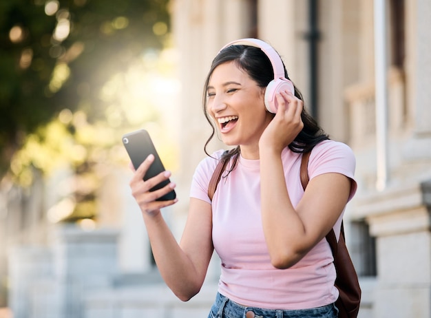 Casque de musique ou appel vidéo par une femme en ville pour voyager heureux et sourire sur fond de construction Podcast radio et étudiante en voyage avec application audio en ligne ou service d'abonnement à l'extérieur