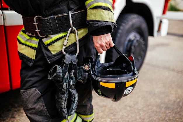 Casque noir en gros plan de la main du pompier