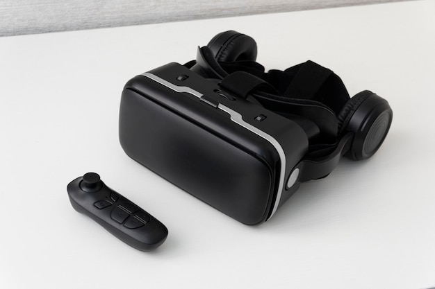 Casque de réalité virtuelle et un joystick sur fond blanc Lunettes modernes noires pour regarder des vidéos à 360 degrés pour un smartphone