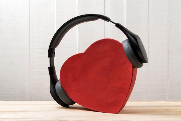 Casque sans fil pleine grandeur portant une boîte en forme de coeur rouge. Concept de musique d'amour. Vue de face