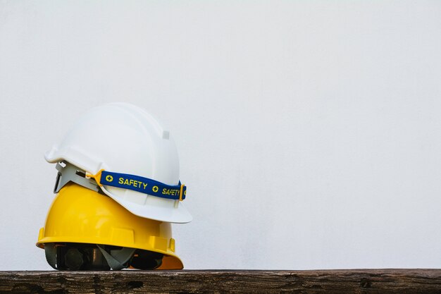 Casque de sécurité, casque de sécurité jaune et blanc sur une table en bois.